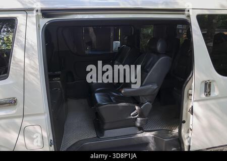 Spacious interior of white passenger van with an open door, showcasing comfortable seats. This vehicle is ready for public transport, shuttle service, Stock Photo