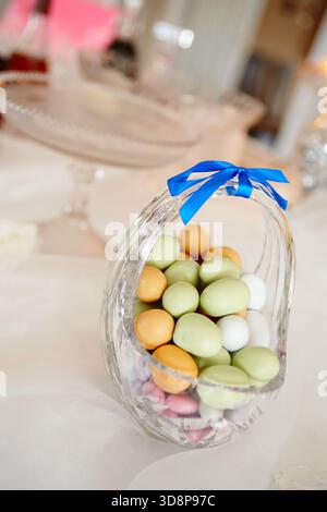 Easter, sweets and tablet in home with eggs for decoration, aesthetic and festive celebration. Empty, background and candy in glass basket for lunch Stock Photo
