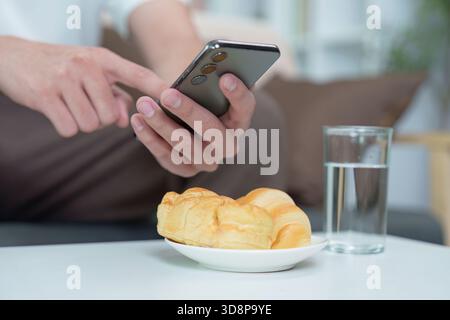 Technology and Lifestyle. Man using smartphone while enjoying breakfast. Stock Photo