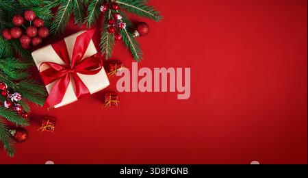 Merry Christmas holiday background. Red Christmas flat lay background with gift box, fir  branches and holiday decorations. Stock Photo