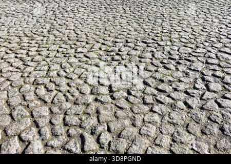 Old cobble stone paving perspective background. Paving stone pavement texture. Old stone sidewalk in Rome, Italy. Cobblestone pavement top view. Stock Photo