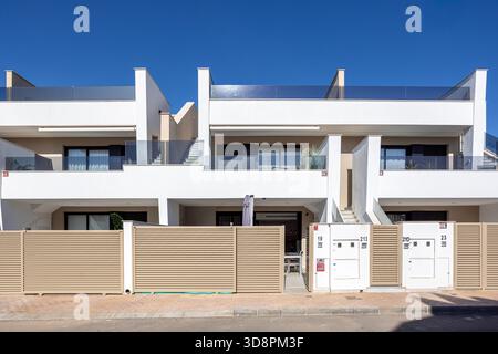 Contemporary multi-unit townhouse facade featuring balconies, stairs, gates, and clean architectural design Stock Photo