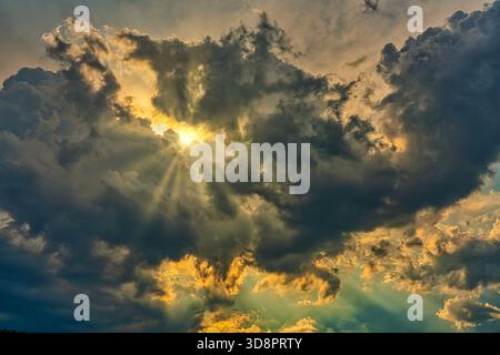 The sun's rays break through the stormy cumulus clouds, creating a spectacular sky. The light contrasts with the dark weather. Abruzzo, Italy Stock Photo