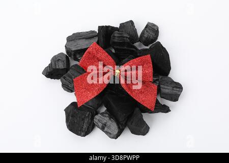 Pieces of black coal with red bow isolated on white, top view. Christmas tradition for kids Stock Photo