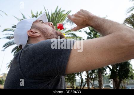 Young man drinking water after an outdoor workout in the city. Stock Photo