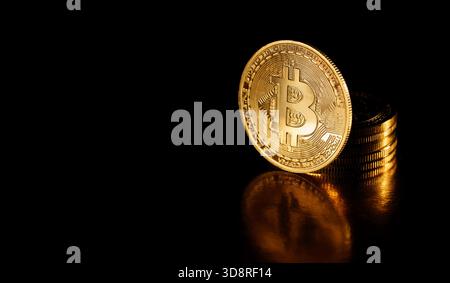 Bitcoin coin isolated on black background. Stack of gold coins with Bitcoin coin in front of it. Golden Bitcoin, crypto currency. Cryptocurrency. Stock Photo