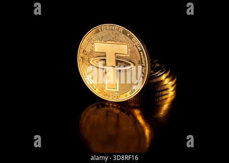 Tether USDT cryptocurrency, physical coin and stack of gold coins. Macro shot. USDT coin isolated on black background. Stack of gold coins with Tether Stock Photo