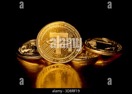 Tether USDT cryptocurrency and gold coins. Macro photography. A USDT coin isolated on a black background. Gold coins with a Tether coin. Stock Photo