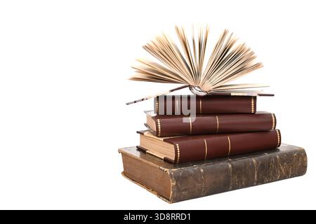 Open antique book placed on a stack of vintage hardcover books isolated on a white background. Symbol of education, literature, wisdom and knowledge Stock Photo
