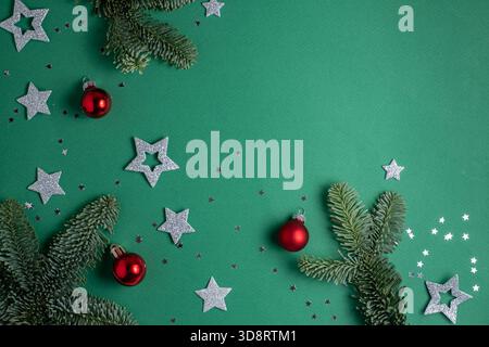 Christmas frame. Fir branches, red Christmas balls and silver stars on a green background. Flat lay and copy space Stock Photo