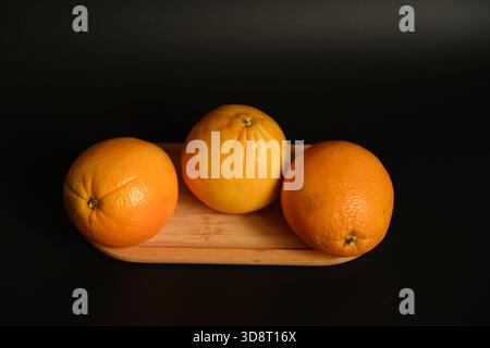 Minimalist Healthy Food: Three Oranges on a Small Wooden Board Stock Photo