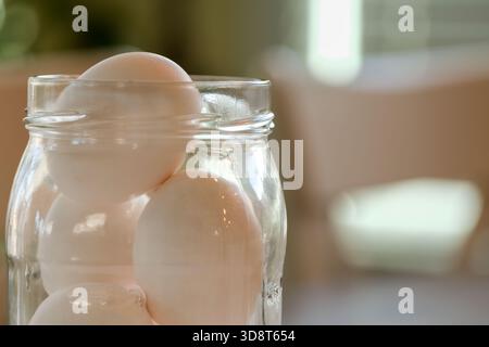 Fresh eggs stacked in mason jar in kitchen Stock Photo