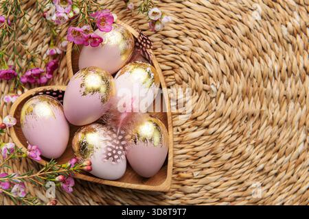 Easter decor. Easter eggs painted in gold in a heart-shaped wooden bowl. The concept of preparation for the celebration. Stock Photo
