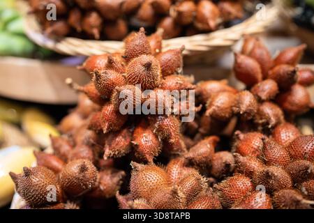 Salak fruits in basket at Asian market. Natural brown skin of exotic tropical fruit sale, unique snake skin fruit, fresh ripe tropical food, salacca zalacca on plate in shop store,snakefruit gourmet Stock Photo