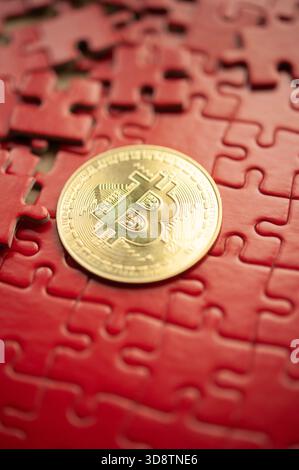 Gold Bitcoin coin placed on red puzzle pieces symbolizing digital currency complexity Stock Photo