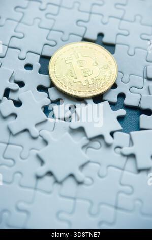 Gold Bitcoin coin placed on a white disrupted puzzle pieces symbolizing  complexity of crypto currency Stock Photo