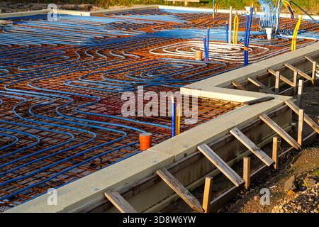 Underfloor heating pipes arranged on reinforced concrete base during modern house foundation work Stock Photo