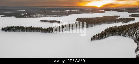Aerial view over forest and snow covered frozen Lahnaselkä lake in Kuusamo in winter, Koillismaa, Northern Ostrobothnia region, Finland, Scandinavia Stock Photo