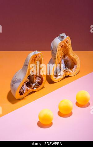 Abstract still life with a cut pumpkin and balls on a multi-colored background Stock Photo