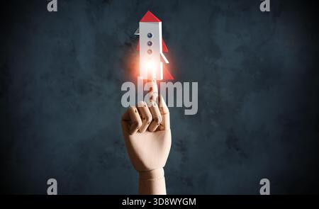 Mannequin hand and digital icon of rocket on virtual screen against dark grunge background. Concept of start Stock Photo