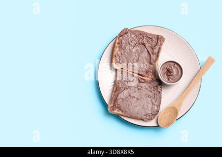 Plate of bread with chocolate spread on blue background Stock Photo