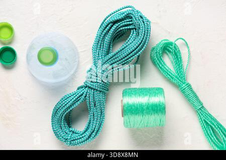 Different ropes with cut-off top of plastic bottle and caps on light background Stock Photo