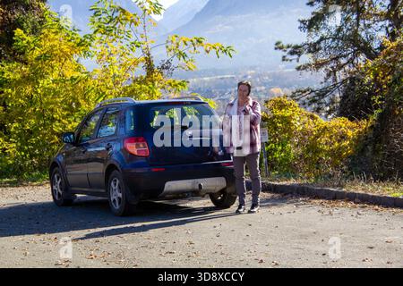 Woman standing on a parking place and using mobile phone. Stock Photo