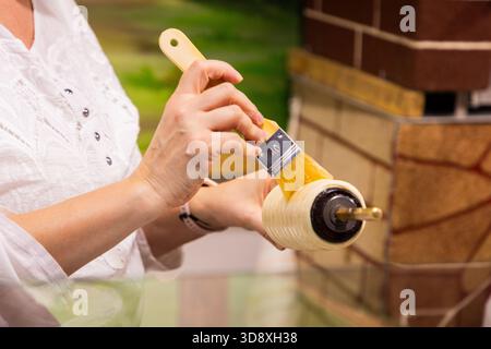 potbelly pig. Woman is painting with a brush on a decorative roller in an artistic workspace, showcasing creativity and craftsmanship Stock Photo