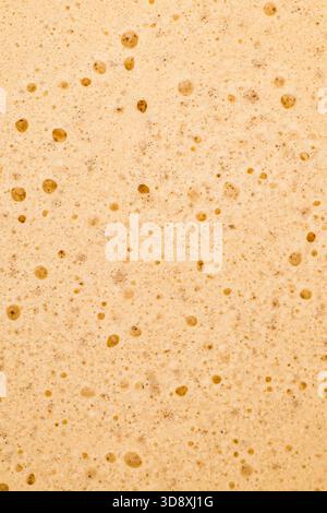 Close up creamy coffee foam texture. Minimal background concept. Coffee bubbles abstract backdrop. Flat lay style. Top view. Stock Photo