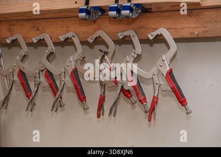 Woodworking clamps hanging from screws on a wooden board Stock Photo