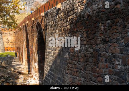 Yerevan Armenia 10.25.2025. A brick wall with a stone archway and a shadow on it. The archway is arched and the shadow is cast on the wall Stock Photo