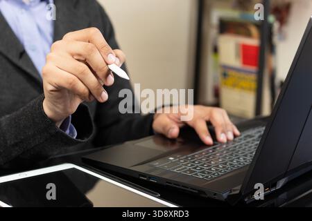 Close up to a modern business man holding a digital pen with his right hand over a tablet at the left side of the screen Stock Photo