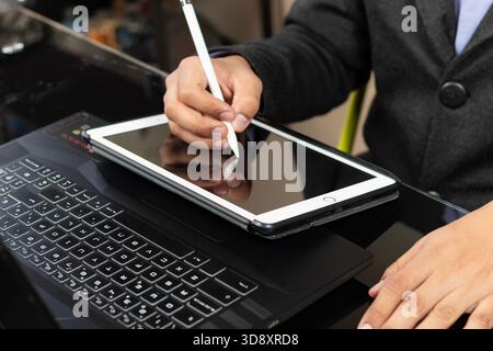 Close up to a male modern business man hands designing something over a white tablet and a black laptop Stock Photo