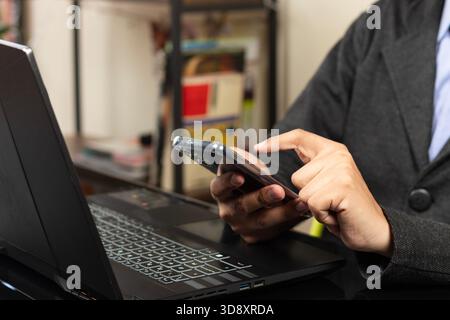 Close up to a modern business man pointing with his index finger to a smartphone display over a laptop Stock Photo