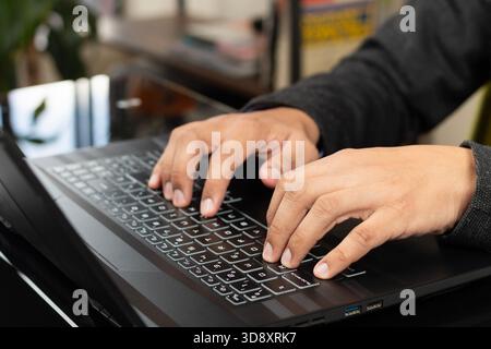 Close up to a male hands typing on a black laptop keyboard Stock Photo