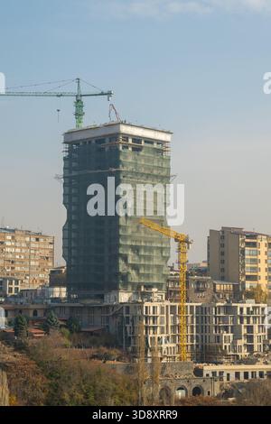 Yerevan Armenia 10.25.2025. A tall building with scaffolding and cranes is being built. The sky is clear and the sun is shining Stock Photo