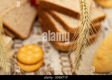 Whole grain bread slices with crispbread crackers and wheat ear on rustic tablecloth Stock Photo