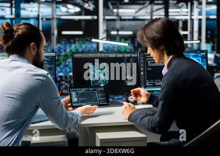 Server farm IT workers deploying artificial intelligence tools to automate repetitive workflows. Data center engineers use tablet, managing datasets used in AI training procedures to streamline tasks Stock Photo