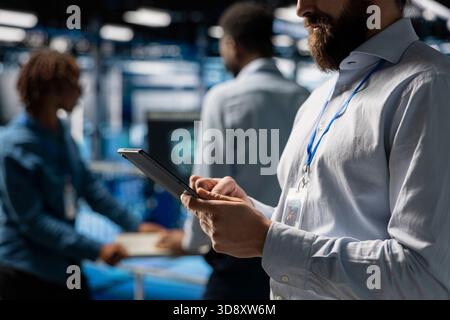Close up of software developer using tablet to review LLM visualization with AI tools, intelligent systems for data center stability. Male engineer works on machine learning automation. Stock Photo