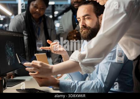 Software developers in data center using computer, verifying firewall configurations. Coworking employees doing brainstorming, performing equipment vulnerability scans in server room using PC Stock Photo