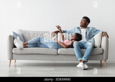 Young black woman switching on air conditioning at home Stock Photo
