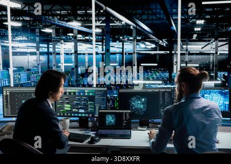 Team of engineers working together in data center, optimizing hardware for AI tasks, increasing workloads. Teamworking server hub colleagues automating system diagnostics using deep learning Stock Photo
