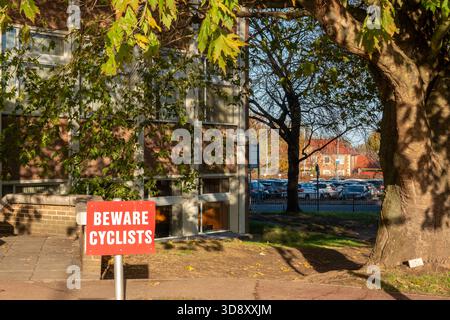 Beware Cyclists sign in Cambridge, UK, near a building and trees on a sunny day Stock Photo