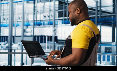 Industry 4.0 industrial plant specialist designs new robotic machines using CAD software on laptop. Smart factory technician using notebook to do tooling for automation equipment, camera A close up Stock Photo