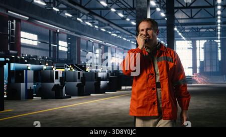 Technician using walkie talkie during job assignment in manufacturing facility, showing the essential communication required to manage tools and machinery. Welding operation. Stock Photo