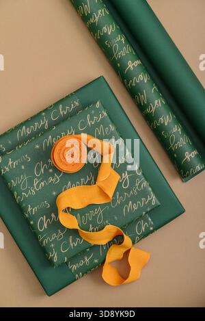 Stack of green gift boxes with yellow ribbon and golden and silver  star-shaped confetti  on golden background, top view Stock Photo