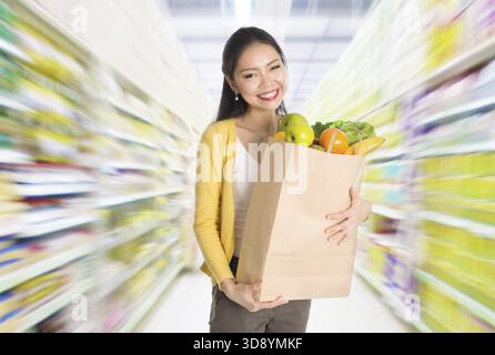 Young Asian woman hand holding shopping paper bag filled with groceries in market or department store Stock Photo
