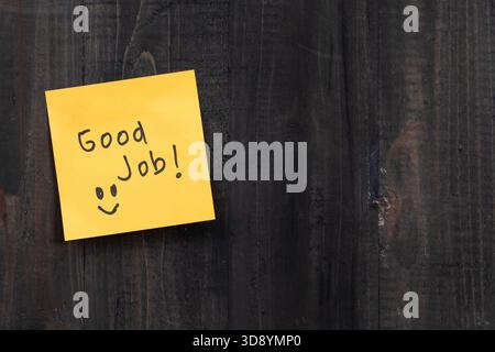 Positive idea concept image using a wooden table and a sticky note with the words Good Job Stock Photo