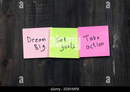 Positive idea concept image using a wooden table and a sticky note with the words Dream Big Set Goals Take Action Stock Photo