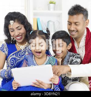 Indian family using digital computer tablet at home. Asian family living lifestyle Stock Photo